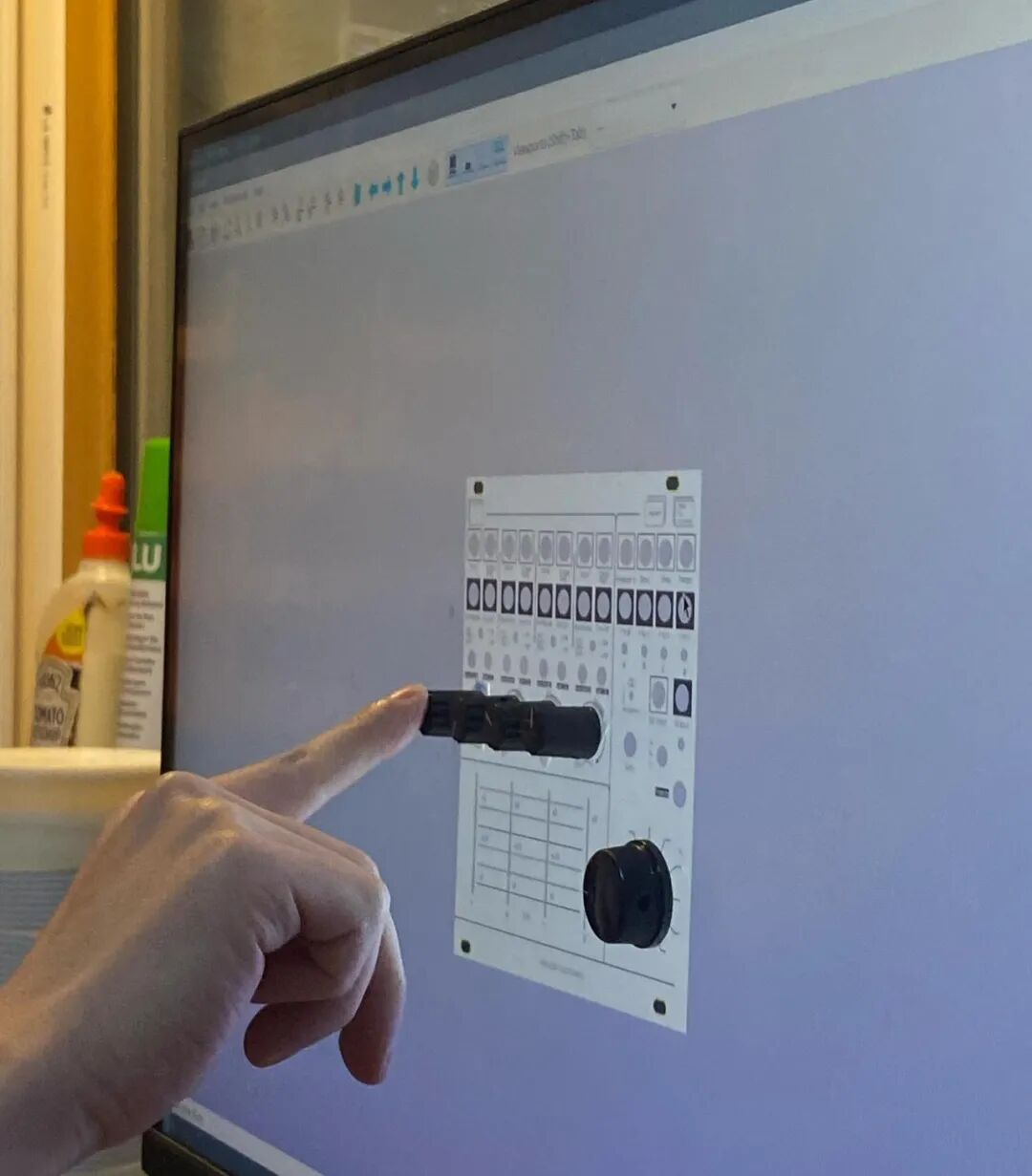 a knob held against a panel layout on screen while sizing the front panel design